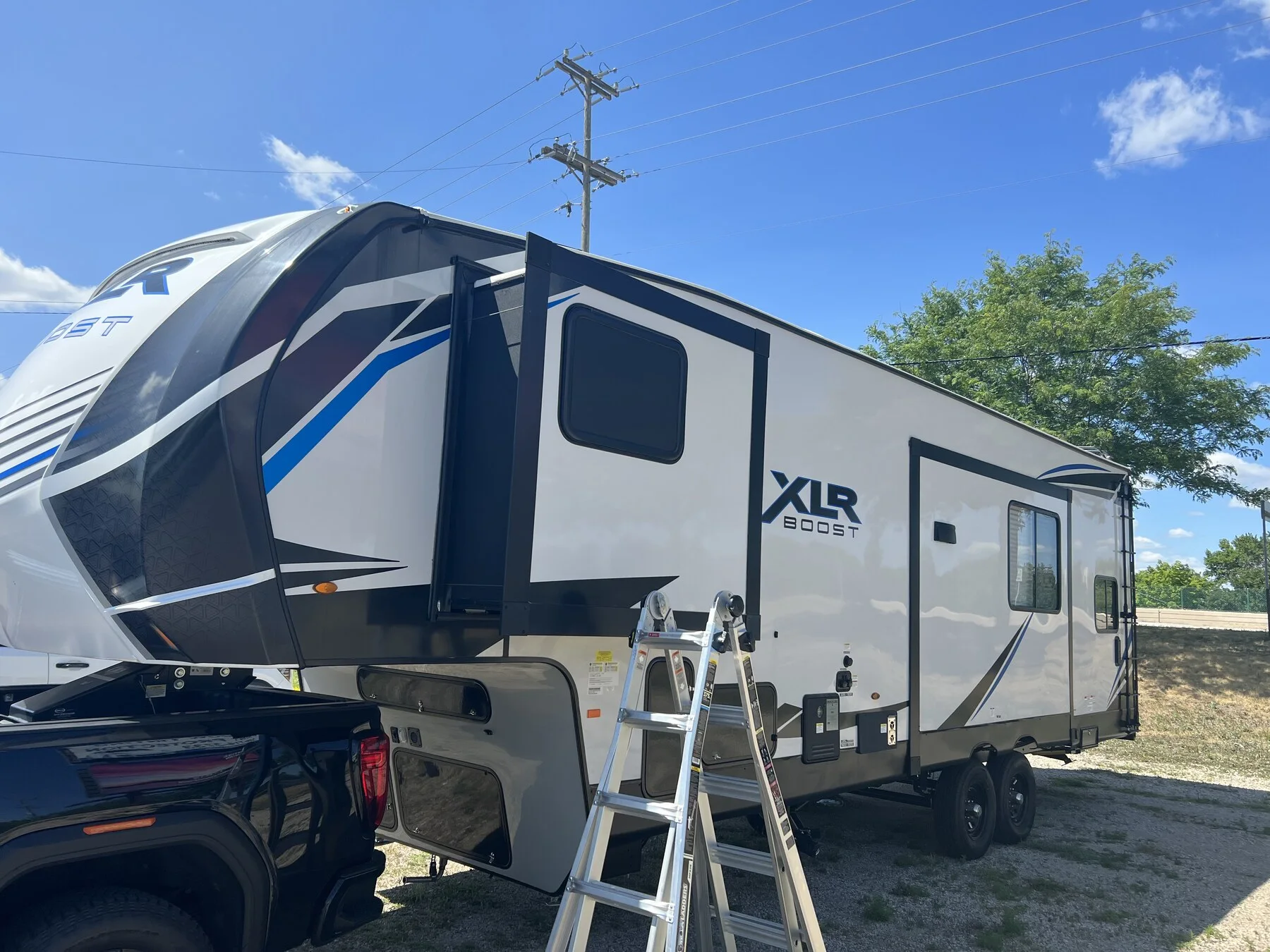 XLS travel trailer with a ladder beside its windows